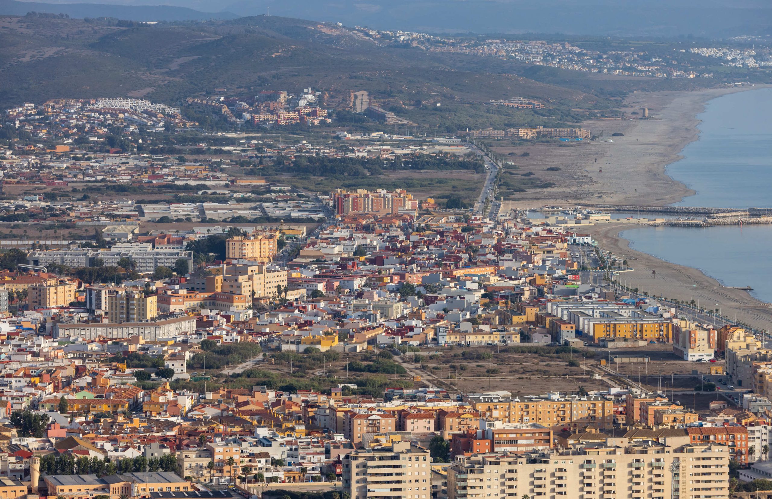 Vista panorámica de una ciudad costera en la Costa del Sol con playa y colinas al fondo.
